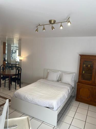 - une chambre avec un lit blanc et une salle à manger dans l'établissement Ben's Studio Lac de Créteil, à Créteil