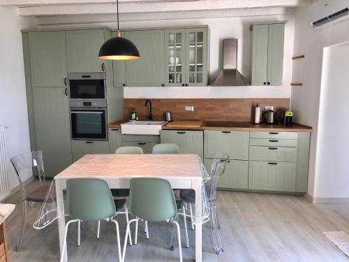 a kitchen with green cabinets and a table and chairs at La Ballerina Bianca - romantica vista lago in Bellano