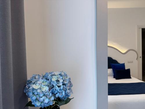 a vase of blue flowers in a room with a bed at Ravello 23 Accommodation in Ravello