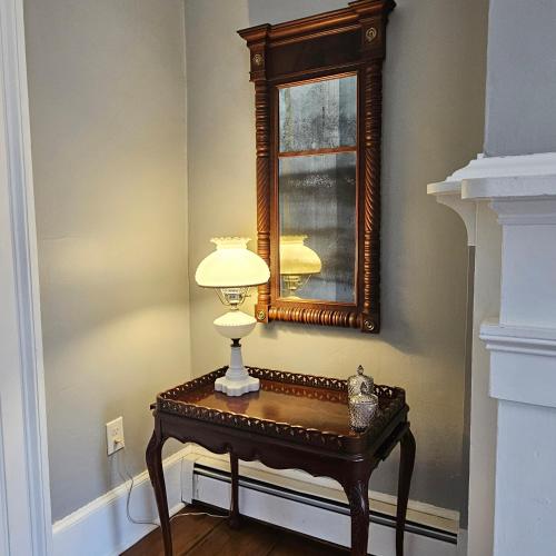 a table with a lamp and a mirror on a wall at Peach Grove House in Warwick