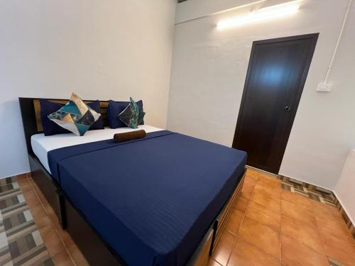 a bedroom with a bed with blue sheets and a door at AquaTerra Comfy stay Varkala beach in Varkala