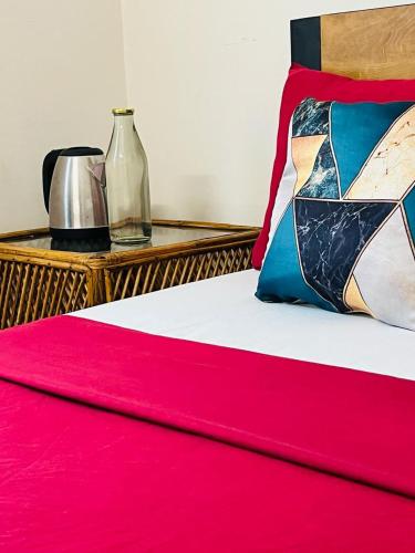a bed with a pink blanket and a table with a vase at AquaTerra Comfy stay Varkala beach in Varkala