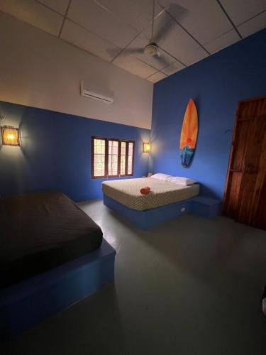 a bedroom with two beds and a blue wall at Buena Onda Backpackers in San Juan del Sur