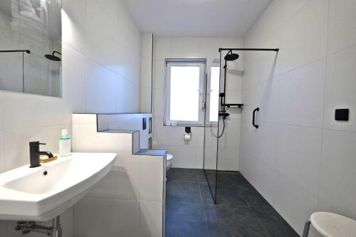 a white bathroom with a sink and a shower at Słoneczny Dom in Poddąbie