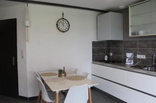 a kitchen with a table and a clock on the wall at Le Cosy Julian in Roye