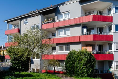 an apartment building with red balconies and trees at Exklusives Business Apartment in Lörrach