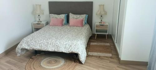 a bedroom with a large bed with pink pillows at Home Away in Vila Nova de Milfontes