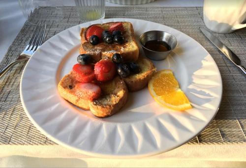 a white plate with french toast with fruit on it at Fairholm Boutique Inns in Charlottetown