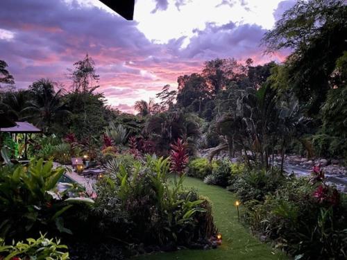 a view of a garden with a river and trees at Sloth Premium Riverfront Jungle Villa with Jacuzzi and Pool in Uvita