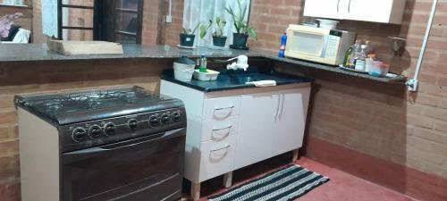une cuisine avec une cuisinière et un micro-ondes dans l'établissement Recanto ágape chalés e cabana, à Rosas