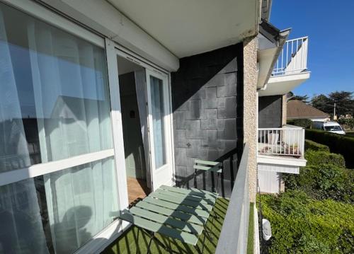 a green bench sitting on the balcony of a house at L'appart Lutin du bord de mer in Luc-sur-Mer