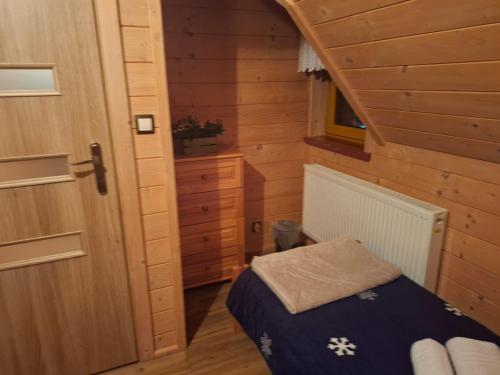 Un pequeño dormitorio con una cama en una cabaña de madera. en Domek do wynajęcia - Podczerwone, en Koniówka