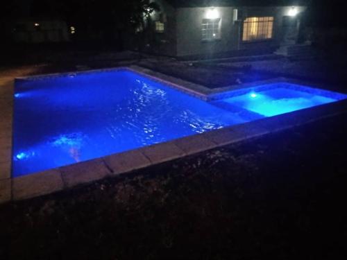 a pool with blue lights in a yard at night at yeta apartments in Livingstone