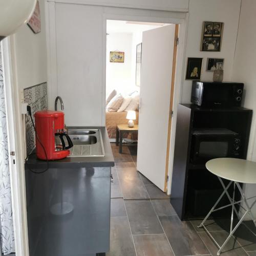 une cuisine avec un appareil rouge sur un comptoir dans l'établissement Maison 48m2 deux chambres cour privé et personnelle pour motos ou voitures 4 Pers proche mairie et bus tram, à Le Pont-de-Claix