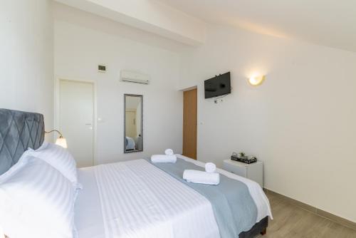 a white bedroom with a bed and a tv at Villa Valamare in Podstrana