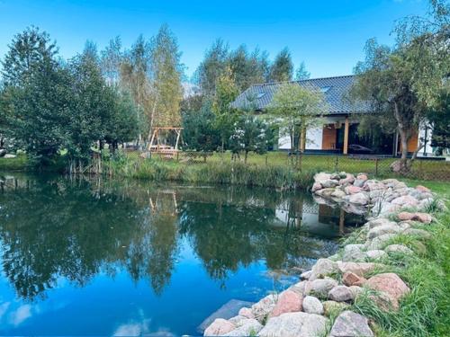 a house and a pond with rocks and a house at Harmony House -Appartement Green in Kołczewo