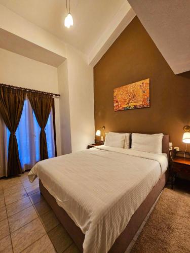 a bedroom with a large bed and a painting on the wall at Hotel Odysseas in Kalyvia