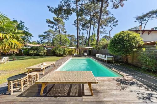 - une piscine avec une table et des chaises dans la cour dans l'établissement Villa bohème chic avec piscine & jardin au Pyla, à La Teste-de-Buch