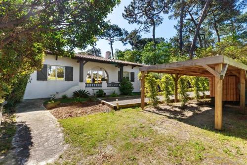 une arrière-cour avec une pergola en bois et une maison dans l'établissement Villa bohème chic avec piscine & jardin au Pyla, à La Teste-de-Buch