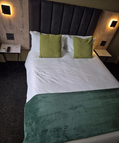 a large bed with two green pillows in a room at Manhattan Hotel in Pretoria