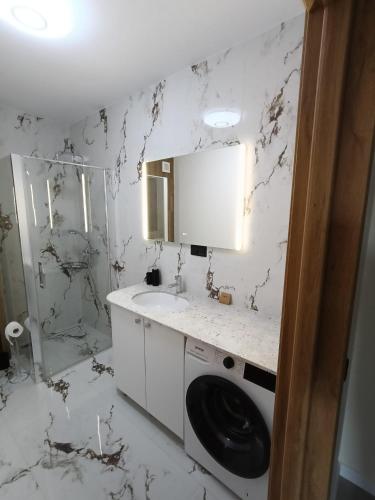 a white bathroom with a sink and a washing machine at NXN Airportstay in Cluj-Napoca
