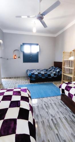 a room with two beds and a ceiling fan at Laila's Home in Siwa
