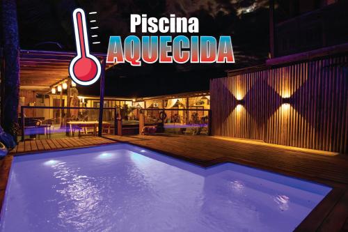 a swimming pool in front of a restaurant at night at Maré Alta - Guest House in Ilha do Mel