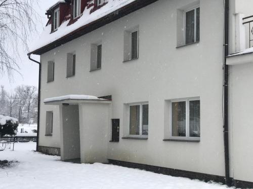 a white house with snow on the side of it at Penzion Horní Bradlo in Horní Bradlo