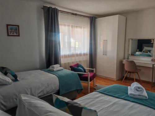 a room with two beds and a chair and a window at Apartman Kristian Zagreb Airport in Velika Gorica