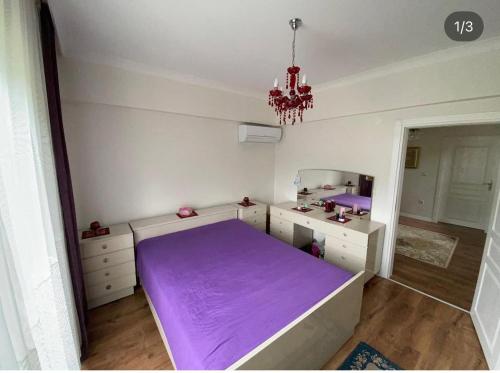 a bedroom with a purple bed and a chandelier at Ömer bey konak in Akcaabat