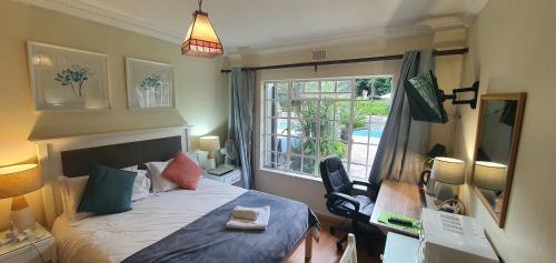 a bedroom with a bed and a window and a desk at PepperTree Guest House Paulshof Jhb Sandton Solar&Borehole in Johannesburg