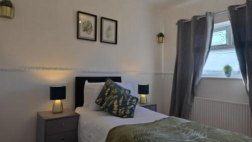 a bedroom with a bed with two lamps and a window at Kabaka - Comfy Birley 3 Bedroom Home in Frecheville