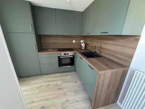 une cuisine avec des armoires vertes et un évier dans l'établissement Appartement ultra lumineux à Berck-Plage pour 6 personnes, à Berck-sur-Mer