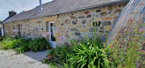 une maison en pierre avec des fleurs devant dans l'établissement Ty Kichen Mor - campagne - wifi, à Crozon