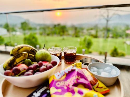 a table with a bowl of fruit and two glasses of soda at Katha Villa 63 - Luxury Holiday Home in Karjat