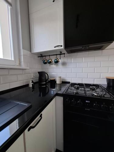 a kitchen with a black stove and white cabinets at Apartament Spokojny Nad Jeziorem in Sztum