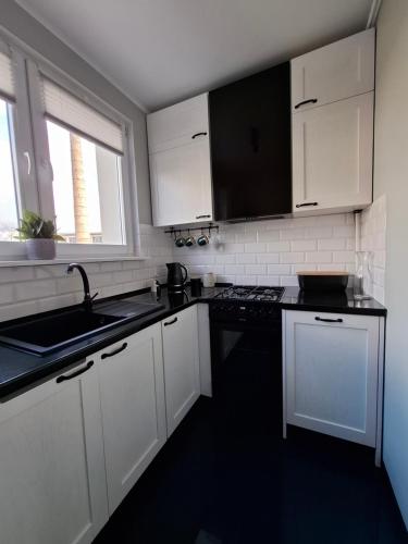 a kitchen with white cabinets and a black counter top at Apartament Spokojny Nad Jeziorem in Sztum