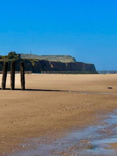 a beach with three wooden posts in the sand at La Descenderie - Bord de mer in Sangatte