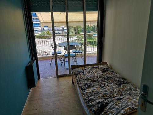 - une chambre avec un lit, une table et un balcon dans l'établissement Mandelieu Iselette du Riou, à Mandelieu-la-Napoule