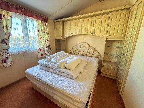 a small bedroom with a bed with white sheets at Great 6 Berth Caravan, Perfect For A Beach Holiday In Hunstanton Ref 13007L in Hunstanton