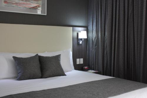 a bedroom with a white bed with black curtains at Casa Inn Galerias Celaya in Celaya