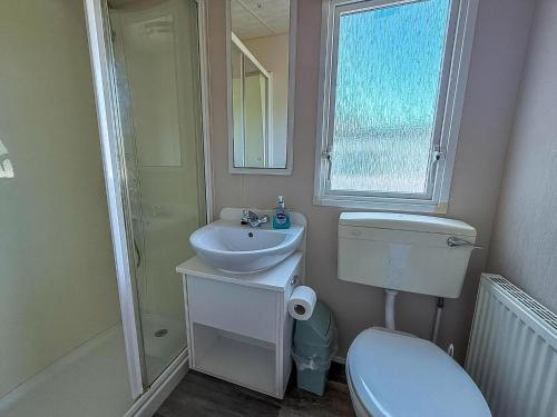 Un baño con inodoro, lavabo y espejo. en Great 6 Berth Caravan With Decking At Manor Park In Hunstanton Ref 23017B, en Hunstanton