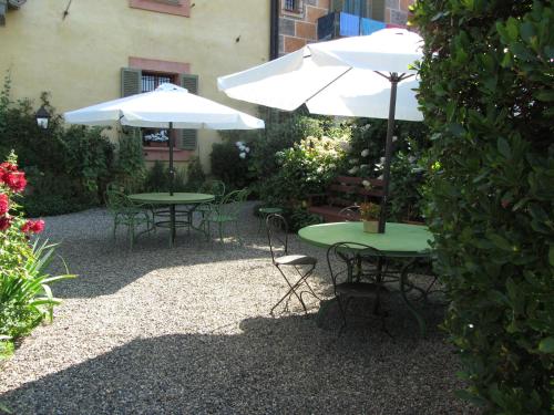 two tables and chairs with umbrellas in a garden at Castello Di Strambinello in Strambinello