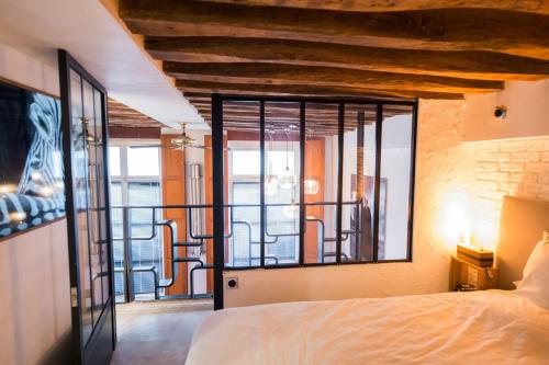 une chambre avec un lit et une grande fenêtre dans l'établissement Artist's Mini Loft - Marais, à Paris