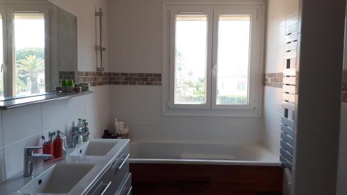 une salle de bain avec deux lavabos et deux fenêtres dans l'établissement Maison familiale Saint Cyprien, à Saint-Cyprien