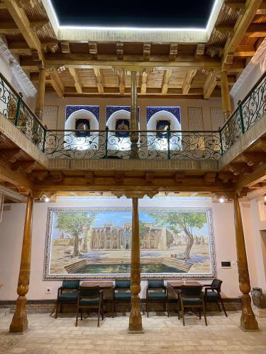 a room with tables and chairs and a painting on the wall at Mukhlisabegim Hotel in Bukhara