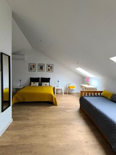 a bedroom with two beds with yellow sheets and a table at Upstairs Home in Ponta Delgada
