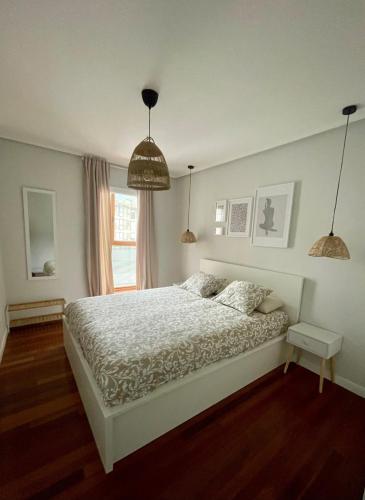 a bedroom with a bed and a window and pendant lights at Marismas de Cantabria cerca de Laredo in Bádames