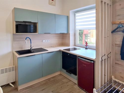 a kitchen with blue cabinets and a sink and a window at Belvárosi Menedék in Nyíregyháza
