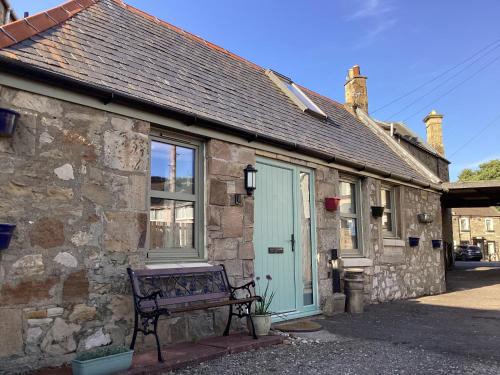 a stone building with a bench in front of it at Cottage in Mid Calder Village near Edinburgh in Mid Calder